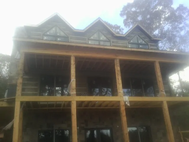 Dormers and porch framing on a large log home under construction — Roof Coating work by our crew in Avon