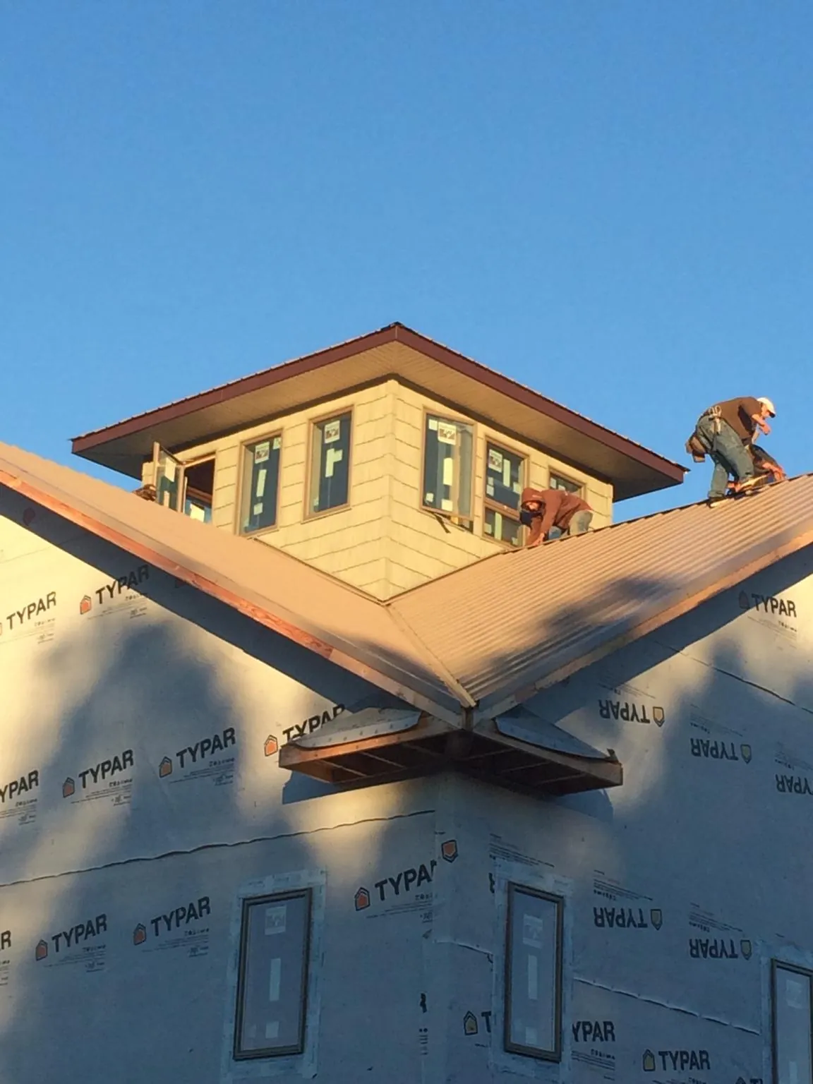 Roofers working around a rooftop cupola on a new metal roof at sunset — Roof Waterproofing in Avon by Roofing Brothers
